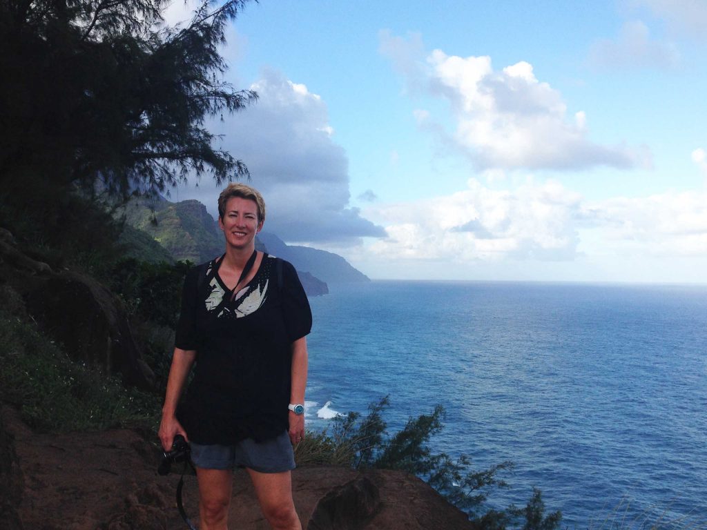 SueWhereWhyWhat standing on the cliffs over looking the sea on the Kalalau Trail in Hawaii with her camera. 10 Top Tips for Hiking as a Solo Female Traveller
