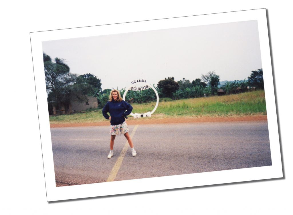 A Young woman standing astride the yellow line of the Equator in Uganda, Africa