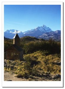A tiny church standing in the afternoon sunshine with a distant glacial backdrop, Estancia Christina, Patagonia, Argentina