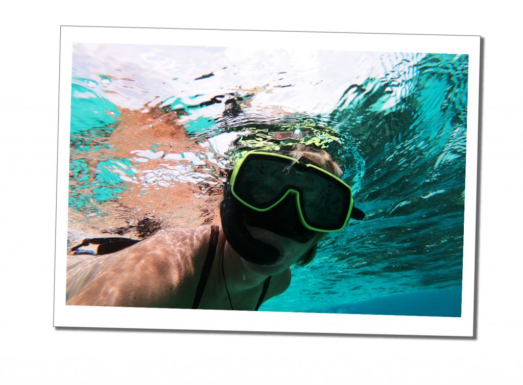 A Woman in a snorkel and mask underwater in a clear blue sea