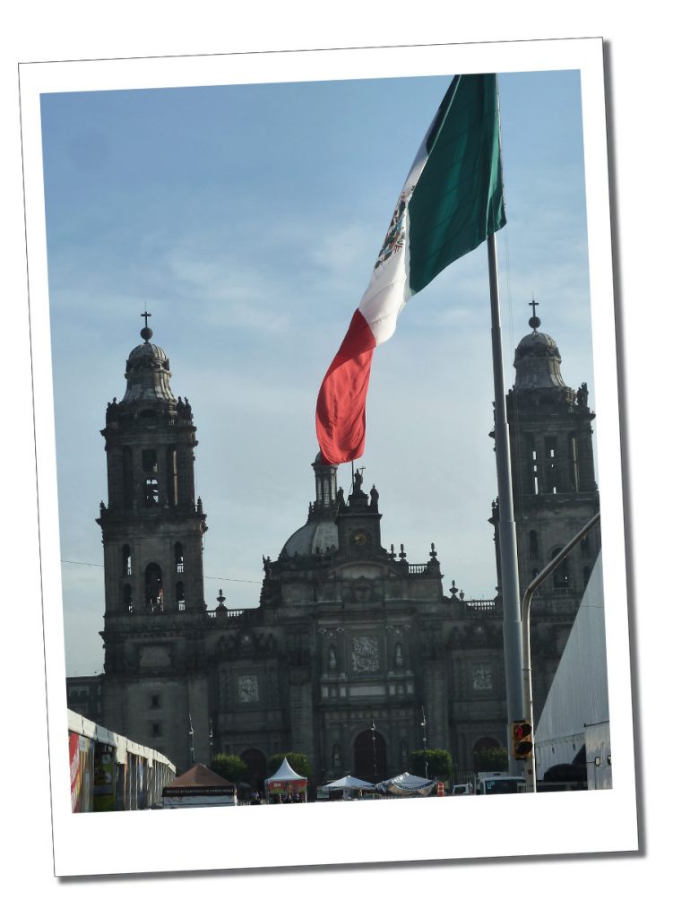 A large building Mexico City behind a Mexican flag