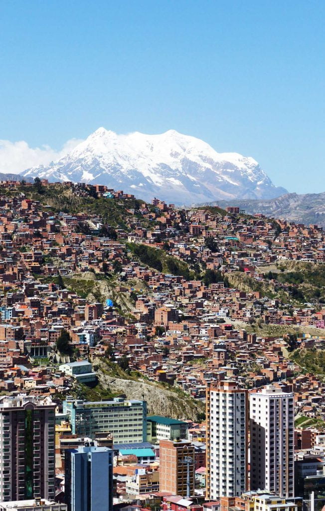 A view of the houses on the hills of La Paz, Bolivia, from Mirador Killi & a giant snow capped peak behind. A First Timer's Guide to Bolivia