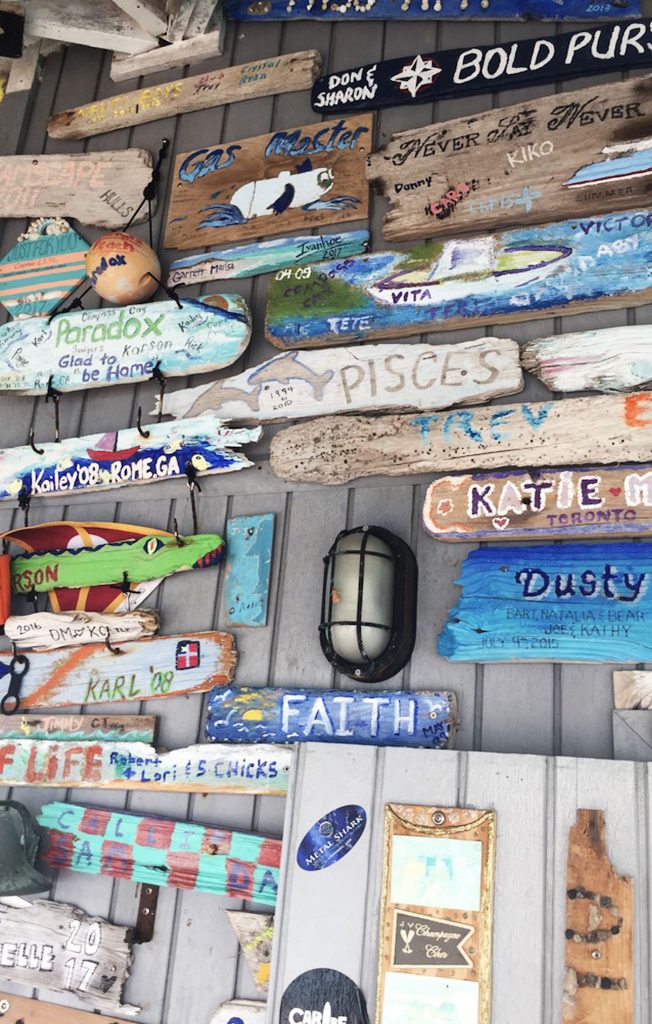 A wall full of Wooden signs and messages at Compass Cay, Exumas