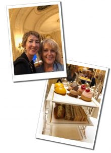 Two women smiling at the sight of an afternoon tea on a two tiered tray