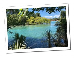 Azure waters viewed from the leafy river bank at Wanaka, New Zealand