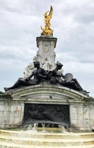 A gold and black Statue and Fountian outside Buckingham-Palace