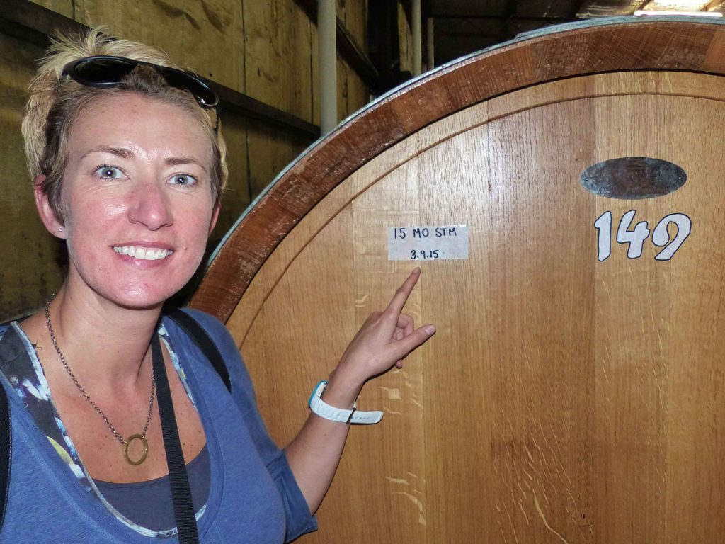 SueWhereWhyWhat, Standing in front of a large wooden vat of Wine, pointing to a sticker dated 3.9.15, vineyards, Australia.