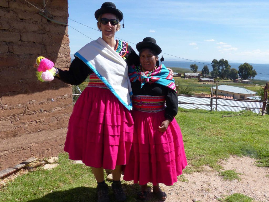 A tall blonde woman and a Cholita standing arm in arm in national costume, Lake Titicaca, Peru