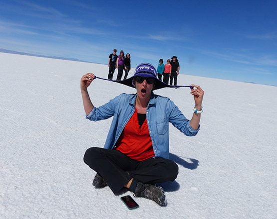 SueWhereWhyWhat smiling & with the use of the flat perspective, pretends to balance 6 people, 3 on each site from her hat flaps, Uyuni Salt flats in Bolivia