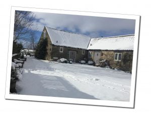 A low level farm cottage set in a snowy landscape