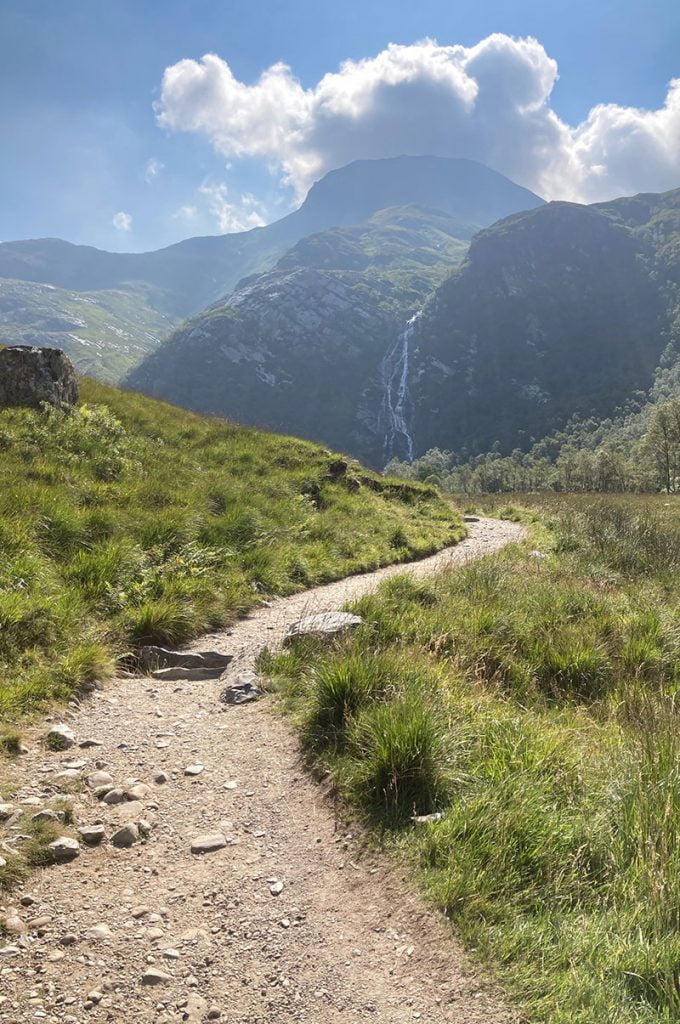 A picturesque gravel path cuts through A Breath taking mountainous heather drenched highland scenary