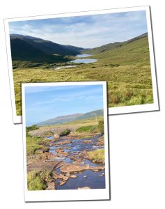 Remote green heath land flanked by rolling hills, dissected by a winding river bed