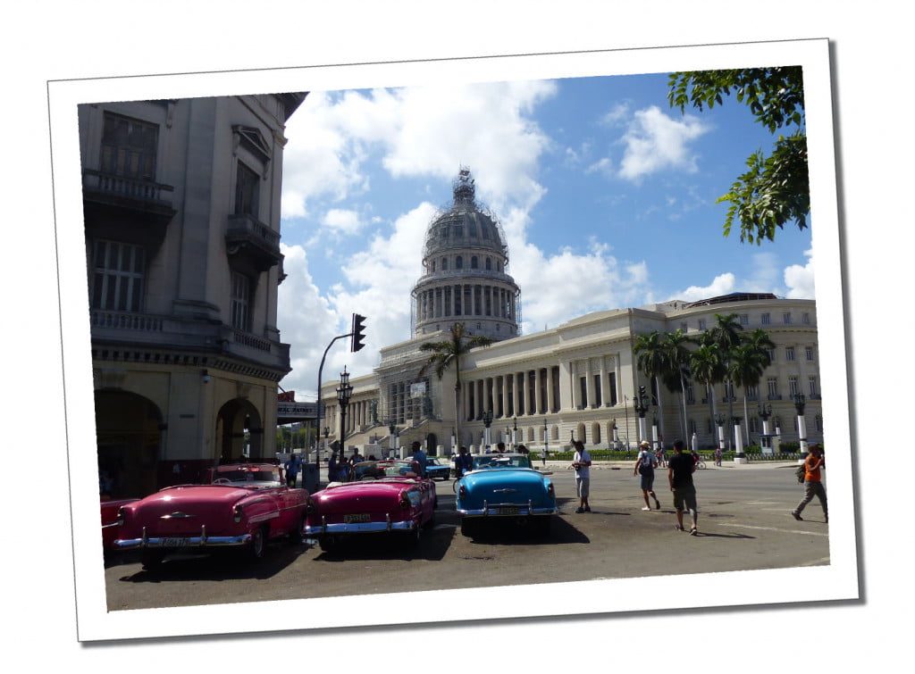 Parked vintage cars with a backdrop of the Capatolio building in Havana