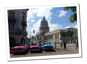 Parked vintage cars with a backdrop of the Capatolio building in Havana