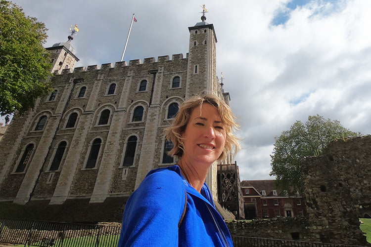 A Smiling blonde woman standing in front of the Tower of London