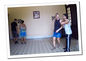 Two couples practising salsa in an empty room of a house with a patterned tiled floor and a picture of a woman on the far wall
