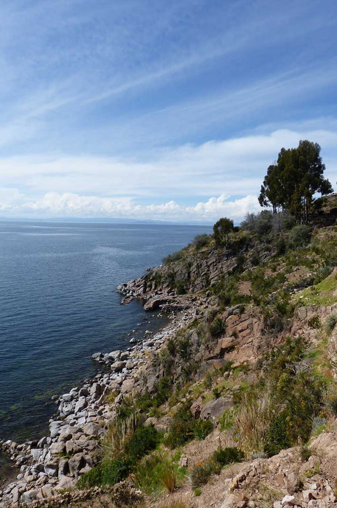 craggy rocks leading to a blue calm lake, Taquiles Island, Lake Titicaca