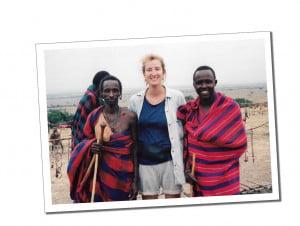 A young woman standing between 2 african tribesmen in pink and blue robes
