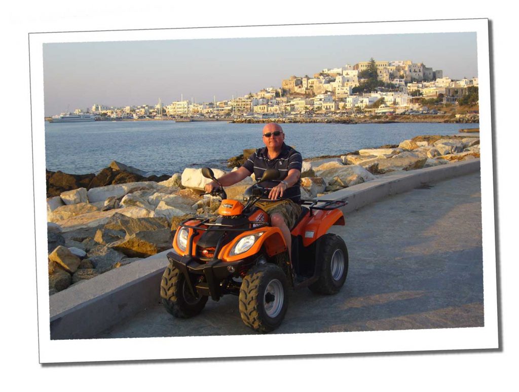 A man riding an orange quad bike by the sea