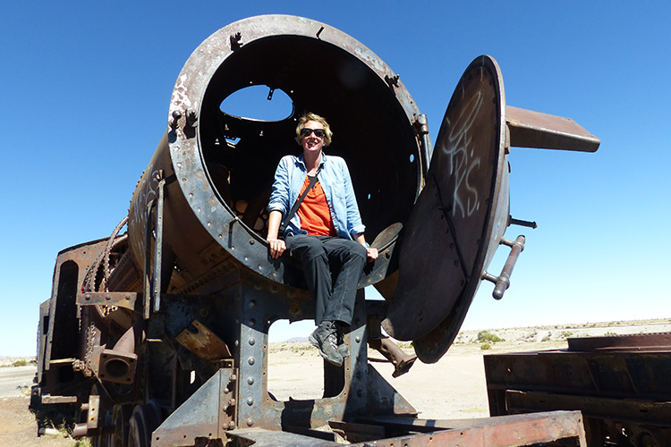 A woman in sunglasses and a denim top sitting in a rusty circular compartment of an old train