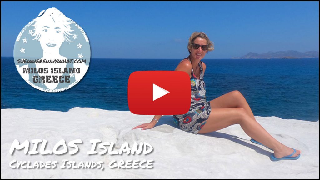 A blonde Woman in a summer dress and sunglasses sitting on the white washed rocks on the serenity of Milos Island on a clear day of blue sea and blue skies - with a white text overlay and red Youtube button