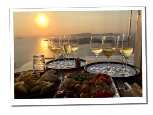A tray of varying sized wine glasses on a table overlooking a dusky seascape