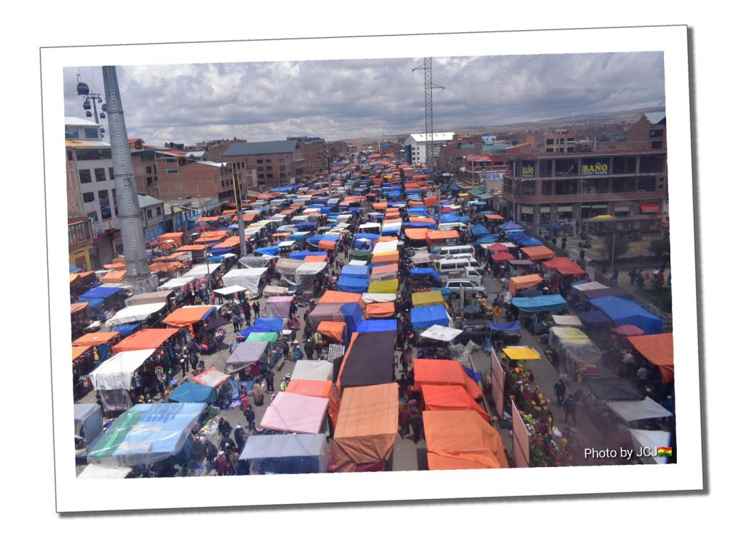 Multi coloured awnings and tarpaulins stretch as far as the eye can see from an overview of a Bolivian street market