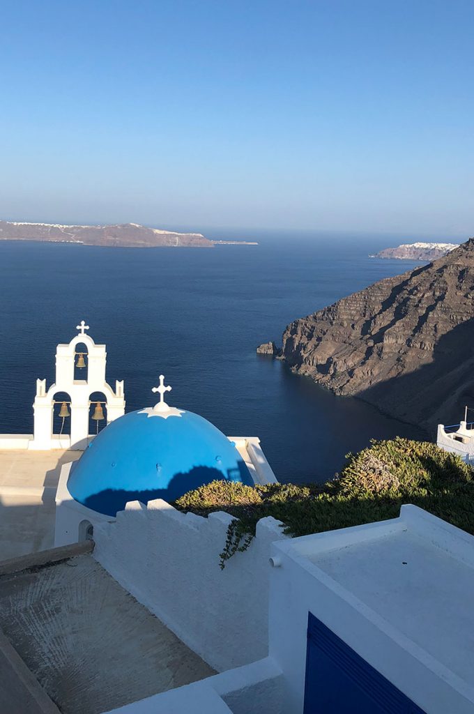 Blue domed Greek churches with white crosses over looking the sea
