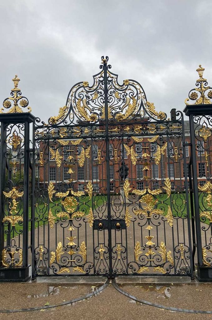 The ornate guilt and black gates outside Kensington place on a wet day
