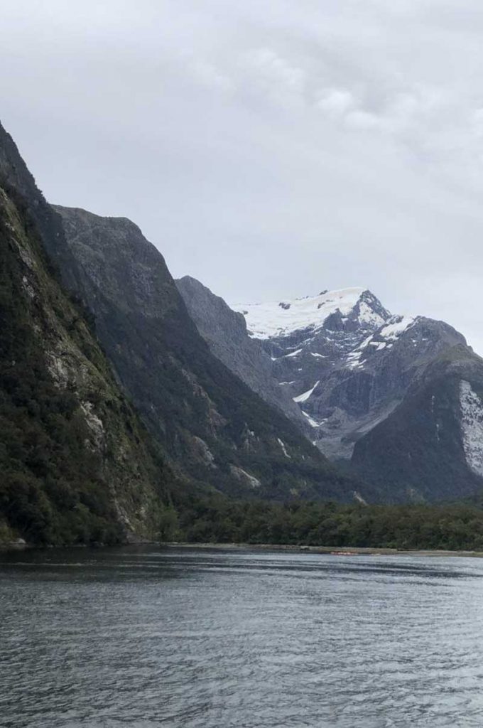 Giant peaks rise from beside the lake at Milford Sound