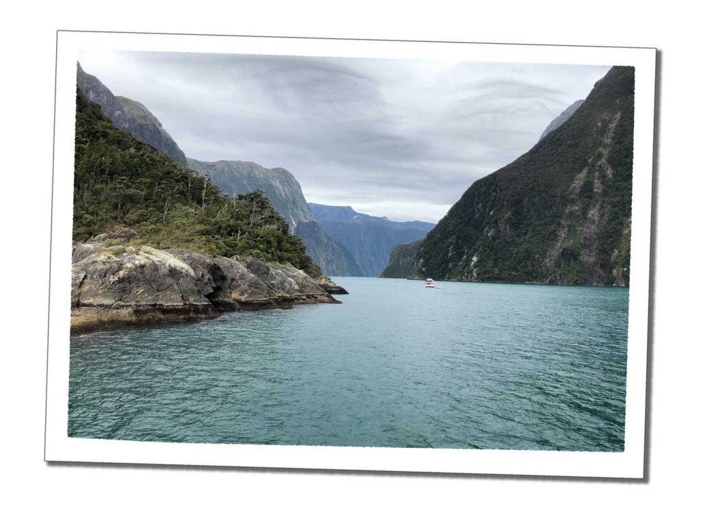 Turquoise water flows between giant rising green mountains as far as the eye can see