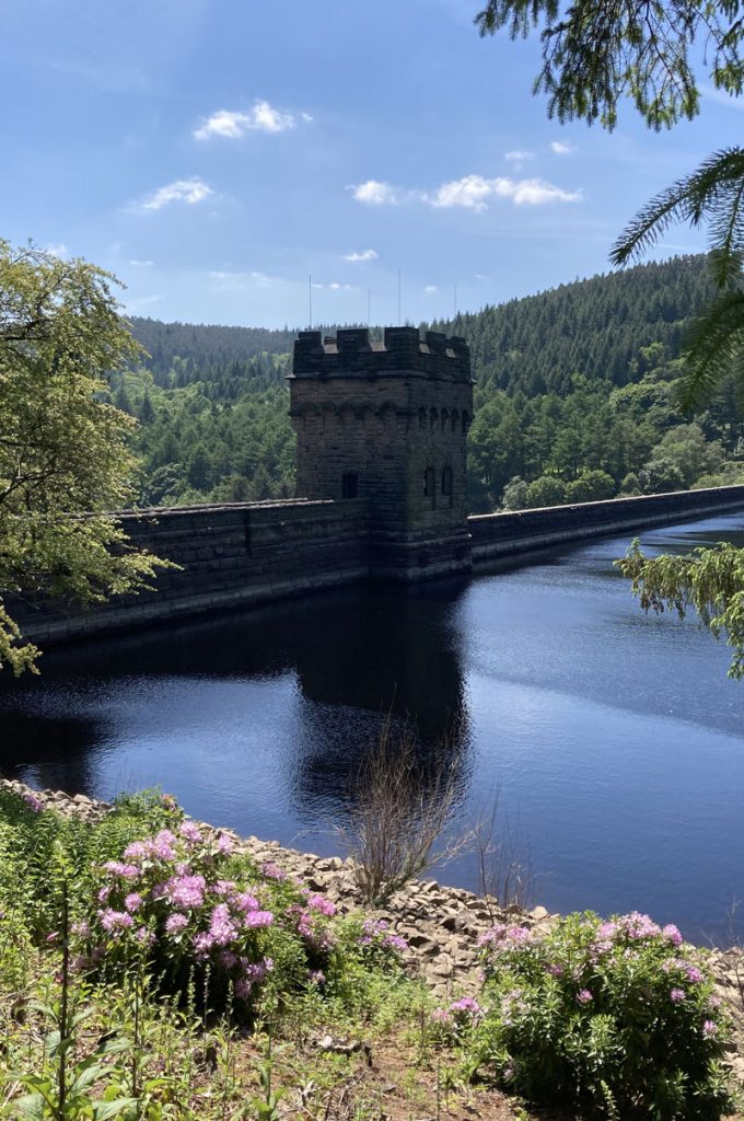 The castle like turret of Derwent Dam & Reservoir refelected in the dark waters it holds