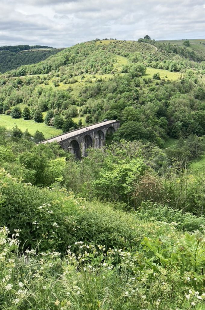 A distant Viaduct amongst green hilly scenery