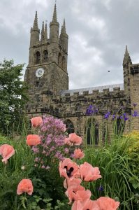A view of an old Church and pink and purple summer flowers