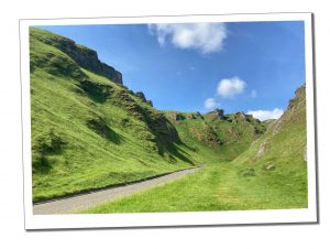 Winnats Pass, with a thin road between green rocky outcrops in the Peak District