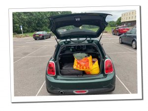 An open car boot full of luggage of a green car parked in a parking bay