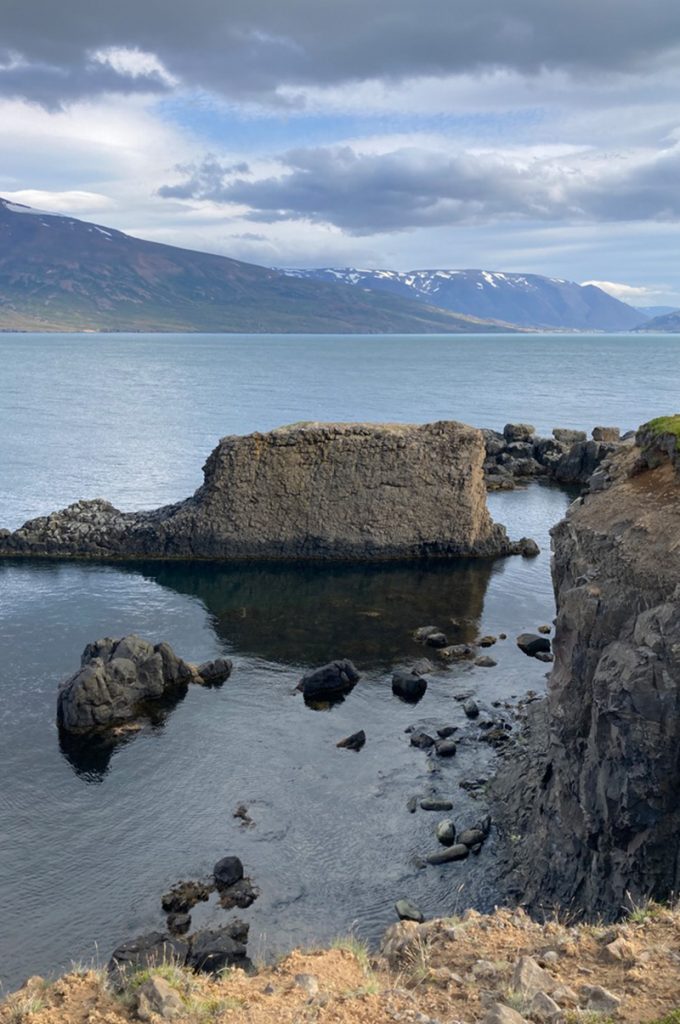 a remote rocky outcrop at the edge of a large flat lake, flanked by dark mountains