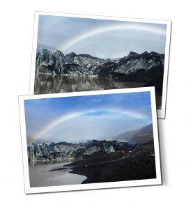 A rainbow arcs high above a still glacial landscape