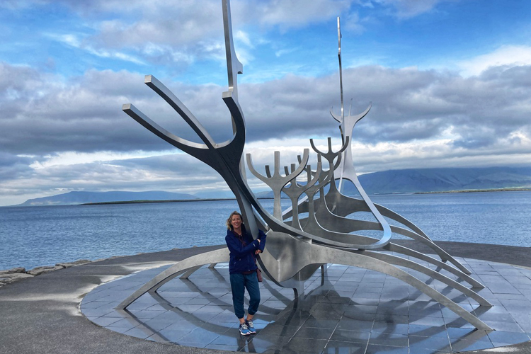 A Woman standing in front of a large metal viking ship sculpture