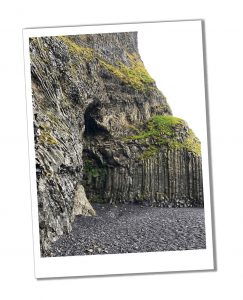A rocky cliff face beside a stony beach