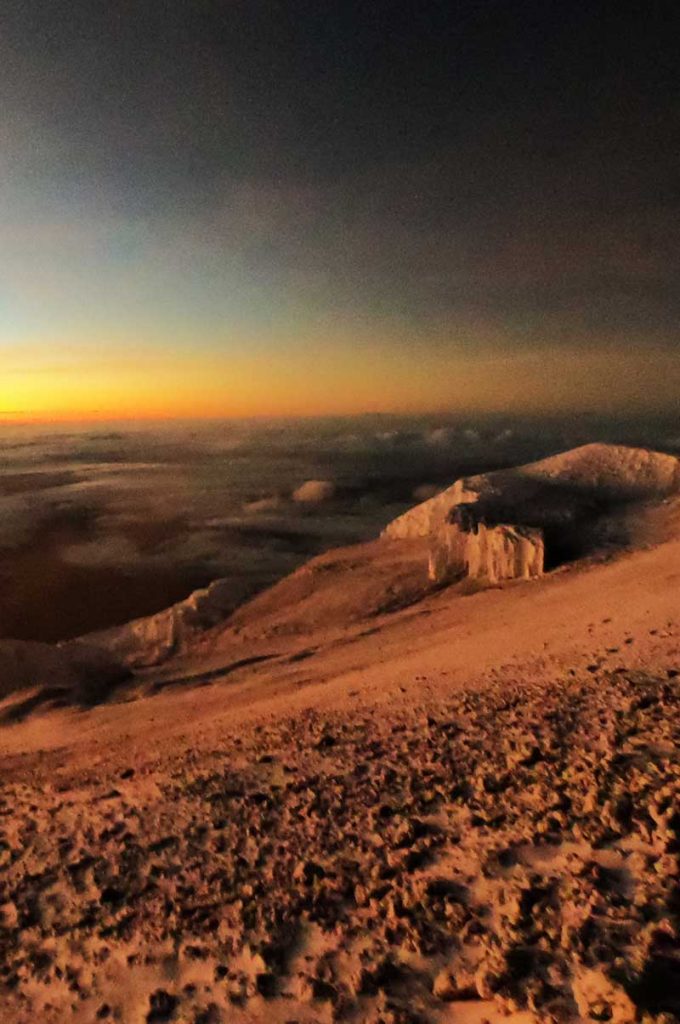 A moonlike scene at the top of a snow covered mountain at day break