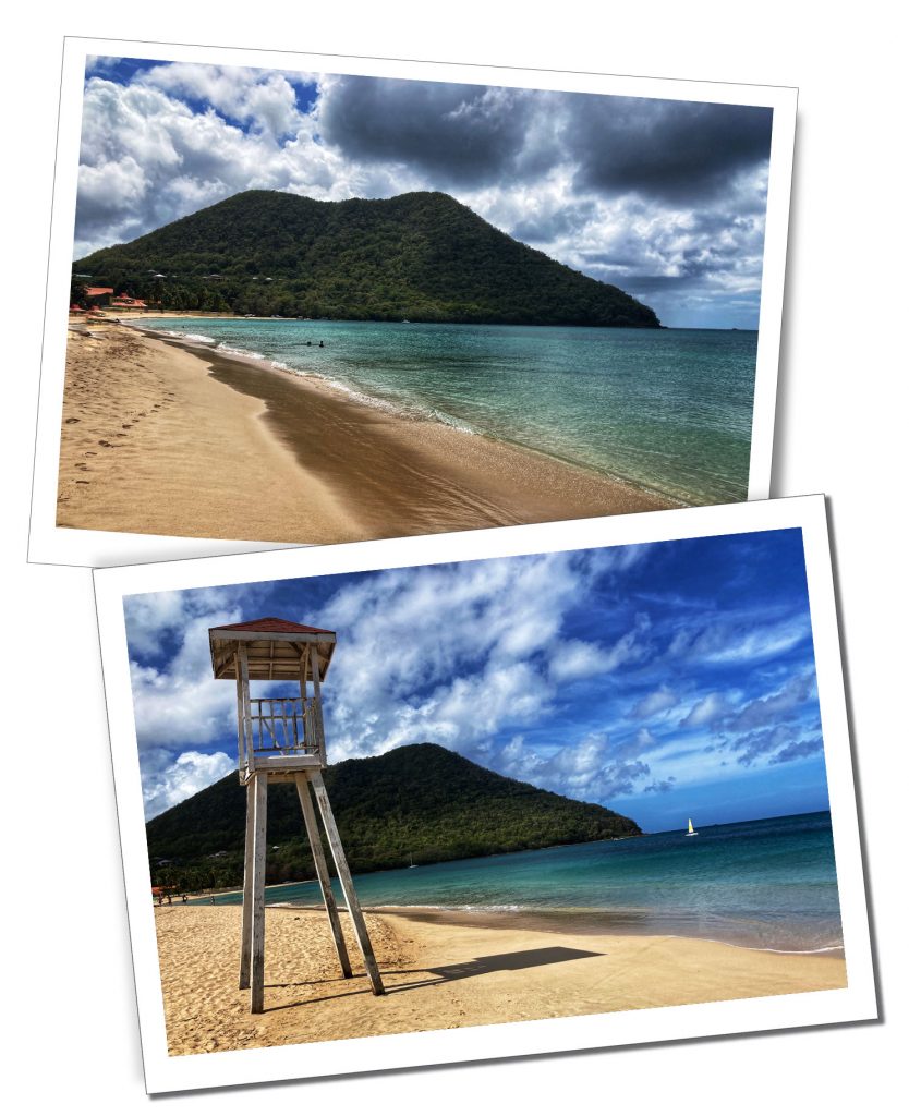 A tranquil tropical sandy beach with a calm sea and green tree covered mountain and an empty wooden lifeguards chair