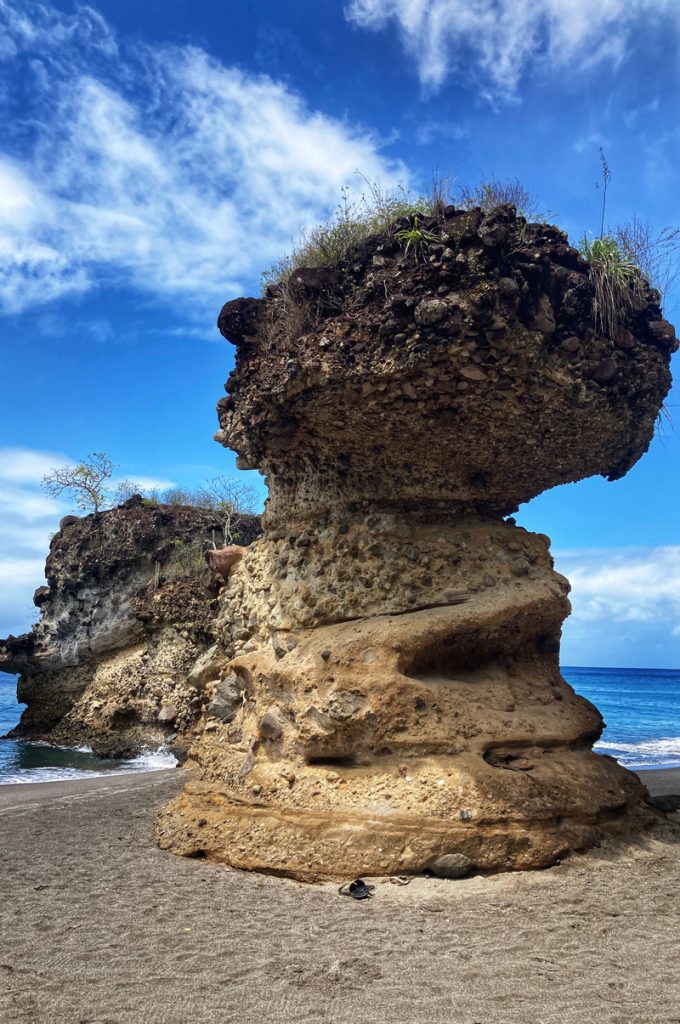 A craggy rock standing on a deserted tropical beach