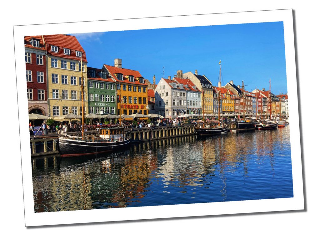 Multi coloured shop fronts overlooking a canal on a bright sunny say in Copenhagen