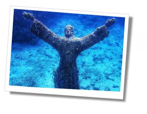 An underwater statue of a man with outstretched arms