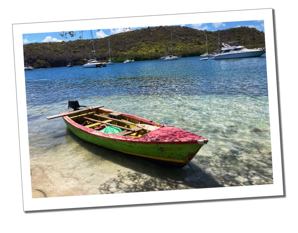 A Colourful red, gold and green rowing baton the sand of a calm caribbean sea