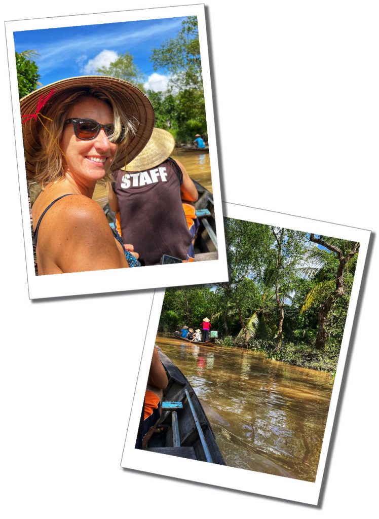 A Woman in a Vietnamese straw hat and sunglasses sitting on a small boat on a brown river behind a person with black t-shirt with the word staff on the back of their t-shirt