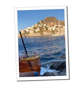 A woman hand holding a Cocktail with sea view and mountain behind