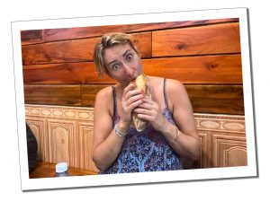 A woman eating a baguette while staring at the camera