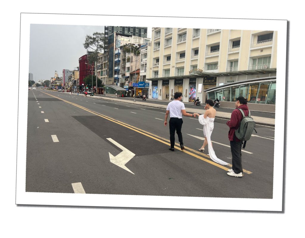 A Wedding couple walking in the road in Saigon Vietnam with a photographer behind